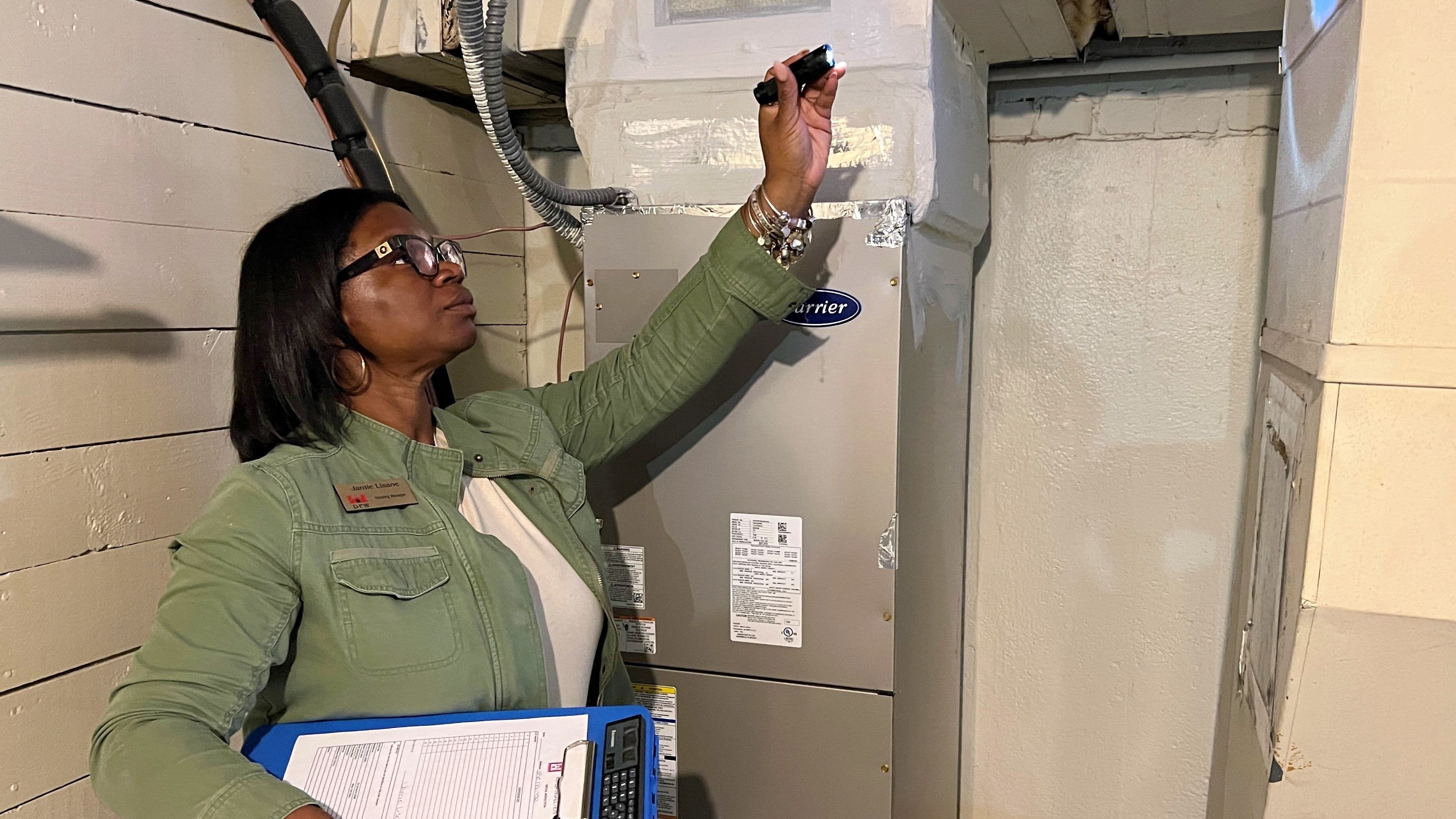 A woman uses a flashlight to inspect a ceiling for mold.