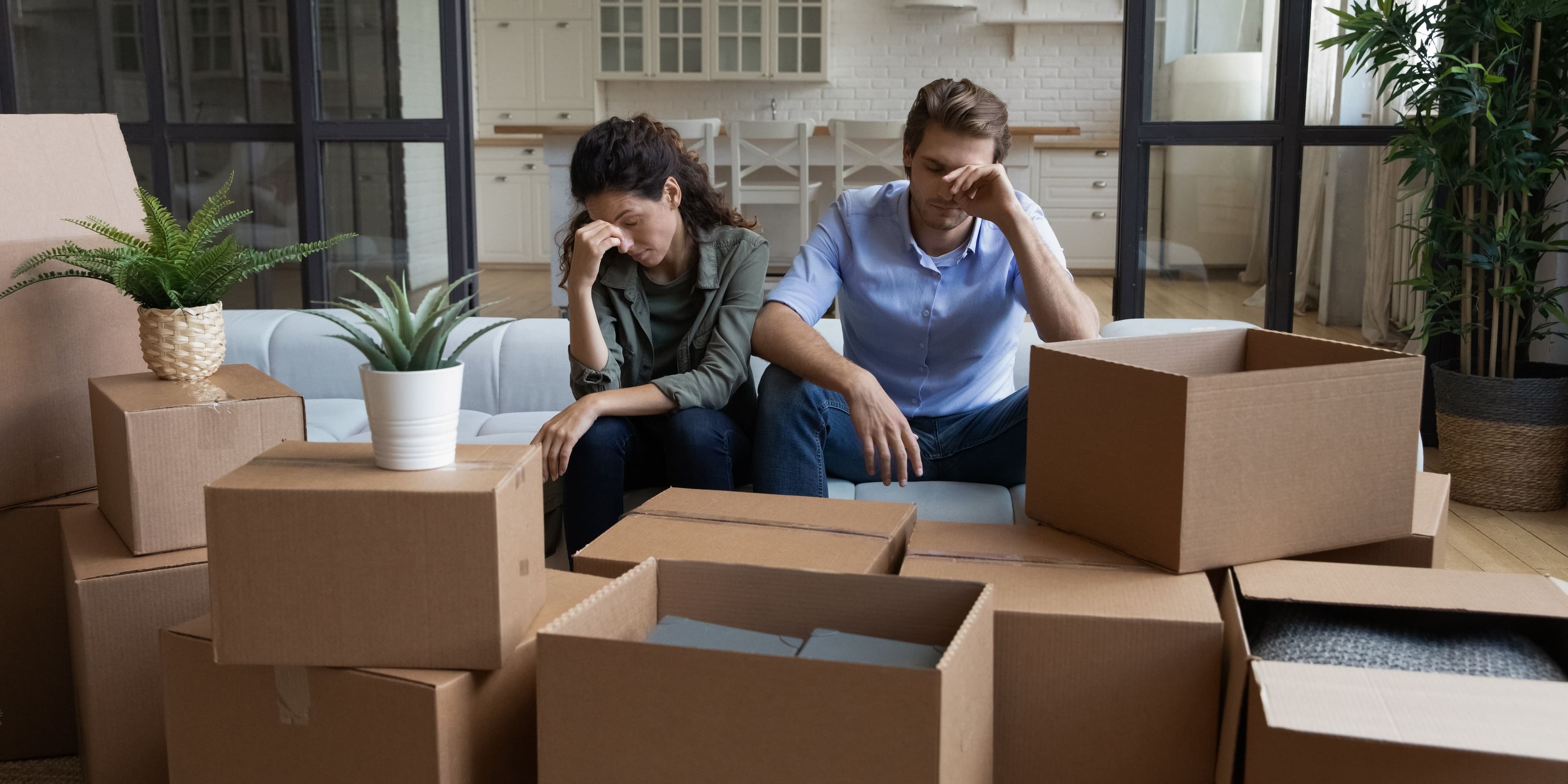 Tired couple in despair during a move surrounded by boxes.